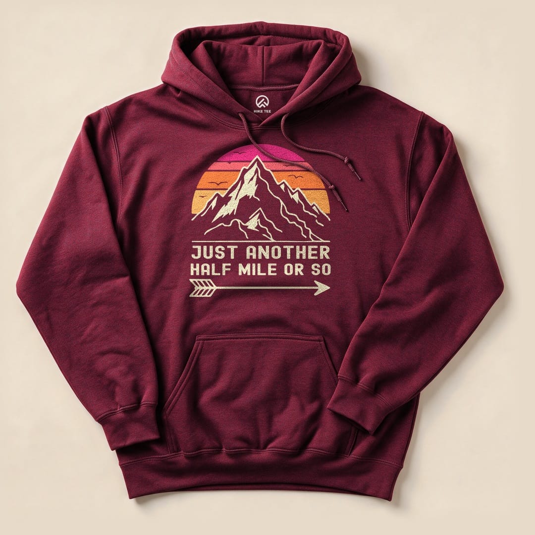 A maroon hoodie featuring a graphic design of mountains and a sunset with the text "JUST ANOTHER HALF MILE OR SO".