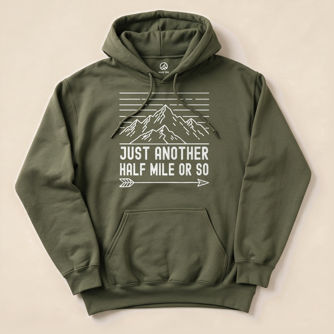 An olive green hoodie featuring the slogan "Just Another Half Mile Or So" above a mountain graphic and decorative lines.