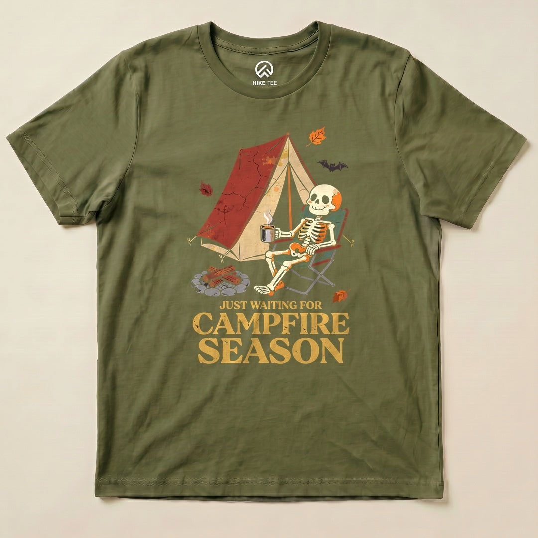 Military Green Just Waiting for Campfire Season Shirt with a skeleton in a camp chair by a tent graphic