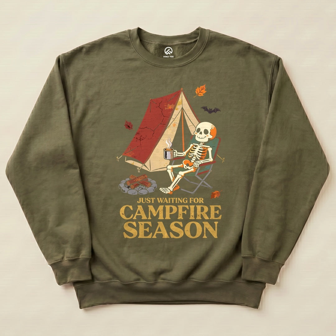 The "Just Waiting for Campfire Season Sweatshirt" features a graphic of a skeleton relaxing in a camping chair by a tent.