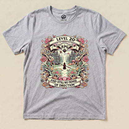 The graphic t-shirt features a whimsical design with the text "Level 20 RPG" and "AND STILL NO SENSE OF DIRECTION" surrounded by flowers and a scenic nature background.
