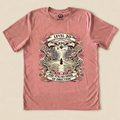 Graphic t-shirt featuring a whimsical design with "Level 20 RPG" and the slogan "AND STILL NO SENSE OF DIRECTION" on a pink background.