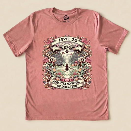 Graphic t-shirt featuring a whimsical design with "Level 20 RPG" and the slogan "AND STILL NO SENSE OF DIRECTION" on a pink background.