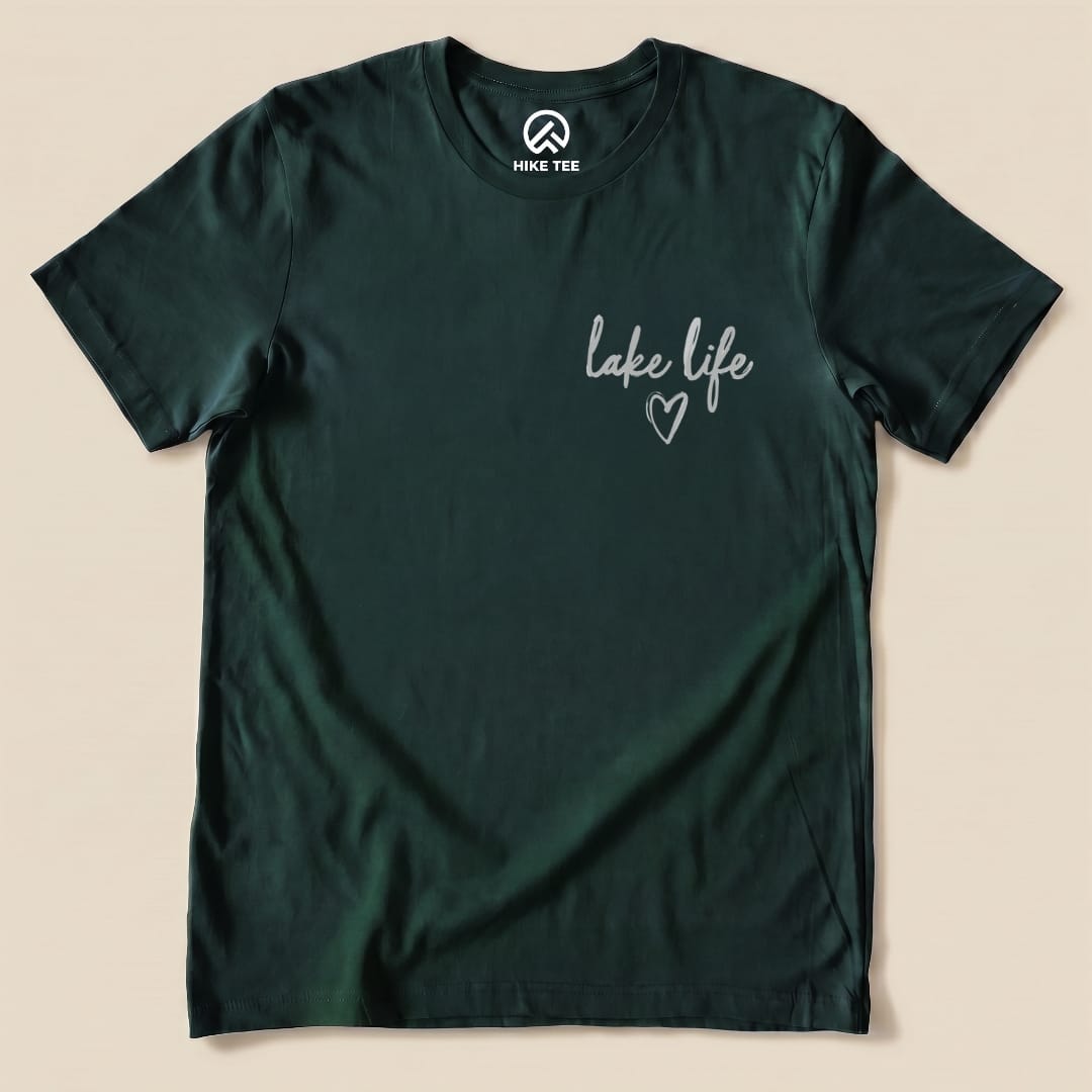 A graphic t-shirt in dark green featuring the phrase "lake life" with a heart design, part of the Like Life Shirt collection.