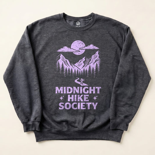 The image features a charcoal sweatshirt displaying a graphic design of mountains, a moon, and the text "Midnight Hike Society" in purple.
