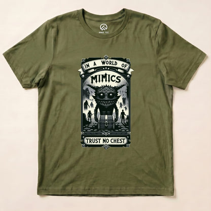 A flat olive green graphic t-shirt features a design with the words "In a World of Mimics" and a creature beside a treasure chest, saying "Trust No Chest.