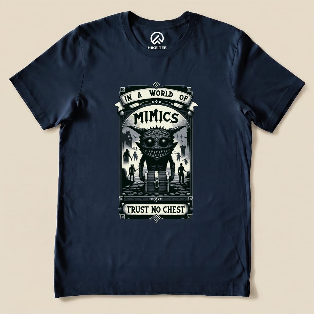 A navy graphic t-shirt featuring the "Mimics Shirt" design, with the slogan "In a World of Mimics, Trust No Chest" and a creature illustration.