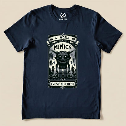 A navy graphic t-shirt featuring the "Mimics Shirt" design, with the slogan "In a World of Mimics, Trust No Chest" and a creature illustration.