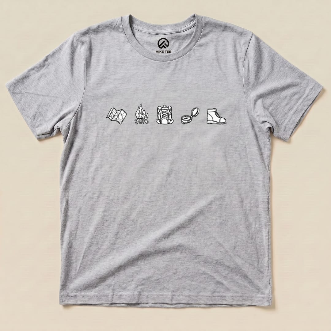 A gray graphic t-shirt features a minimalistic drawing hiking shirt design with icons of a map, campfire, backpack, and boot.