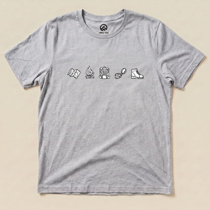 A gray graphic t-shirt features a minimalistic drawing hiking shirt design with icons of a map, campfire, backpack, and boot.