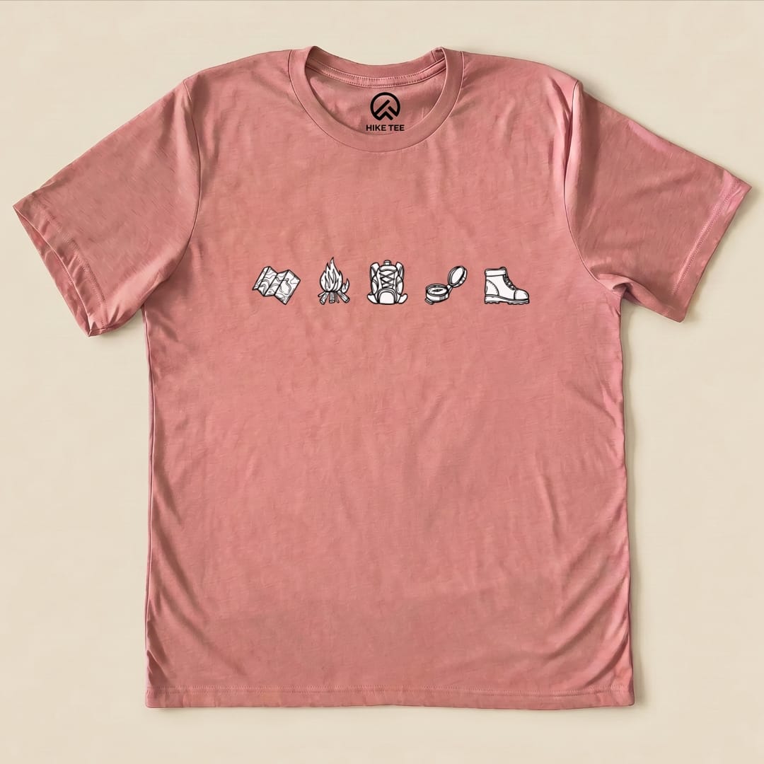 This minimalistic drawing hiking shirt features simple illustrations of a map, campfire, hiking boots, and compass on a dusty rose t-shirt.