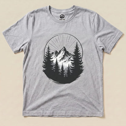 The Monochrome Mountains Shirt features a striking graphic of mountains surrounded by trees, printed on a light gray graphic t-shirt.