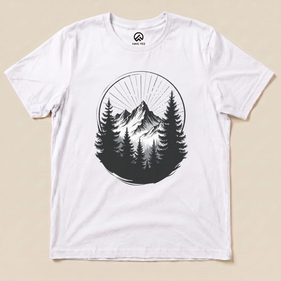 A graphic t-shirt featuring a monochrome mountain design surrounded by tall pine trees, labeled "Monochrome Mountains Shirt.
