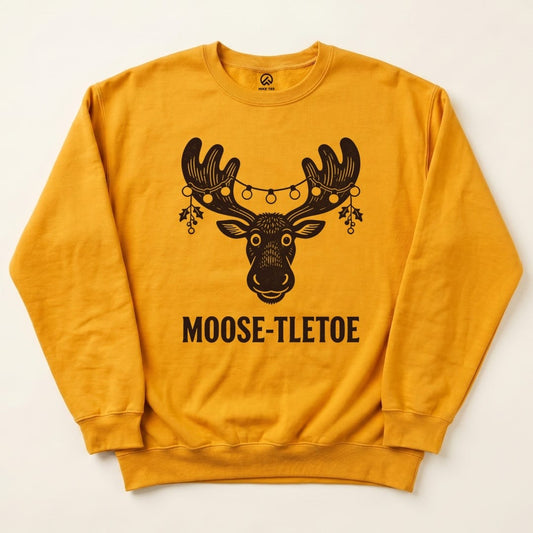 A mustard yellow Moose-tletoe Sweatshirt features a graphic of a moose's head adorned with holiday lights and mistletoe.