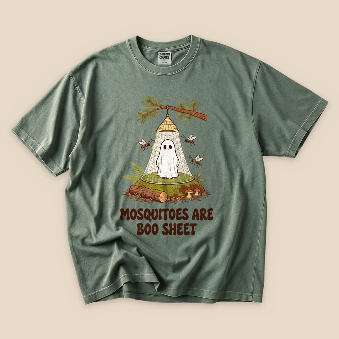 A graphic t-shirt featuring a ghost in a tent with the phrase "Mosquitoes Are Boo Sheet" printed below in a playful font.