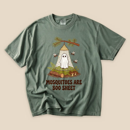 A graphic t-shirt featuring a ghost in a tent with the phrase "Mosquitoes Are Boo Sheet" printed below in a playful font.