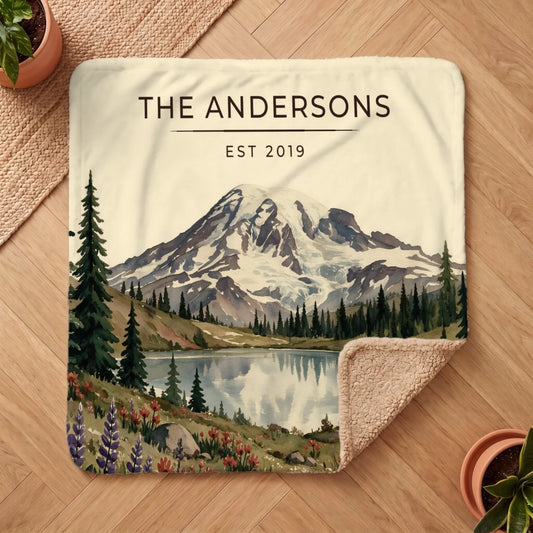 A cozy Mount Rainier Lake Sherpa Blanket featuring a scenic mountain and lake design surrounded by colorful foliage and trees.
