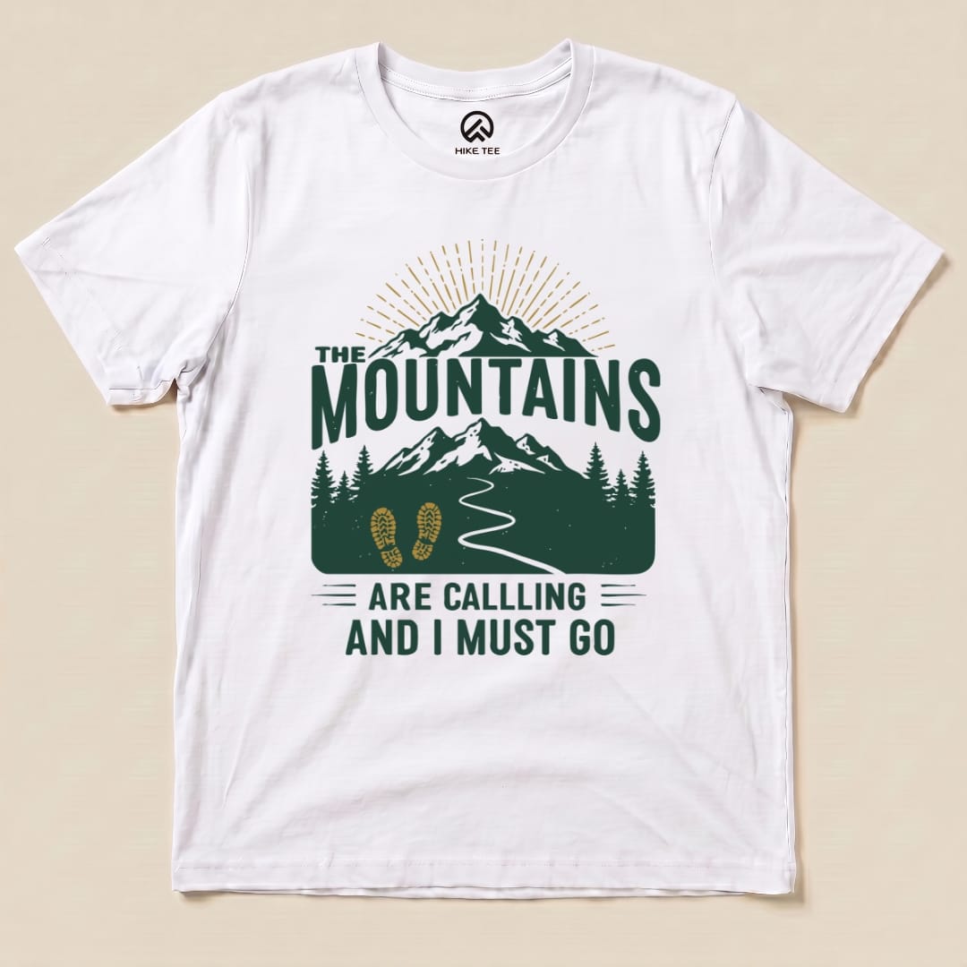 A white graphic t-shirt features the design "The Mountains Are Calling and I Must Go," with mountains, trees, and a winding path.
