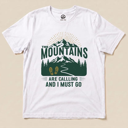 A white graphic t-shirt features the design "The Mountains Are Calling and I Must Go," with mountains, trees, and a winding path.