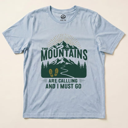 The "Mountains Are Calling Shirt" features a scenic graphic of mountains, trees, and a path, printed on a light blue graphic t-shirt.