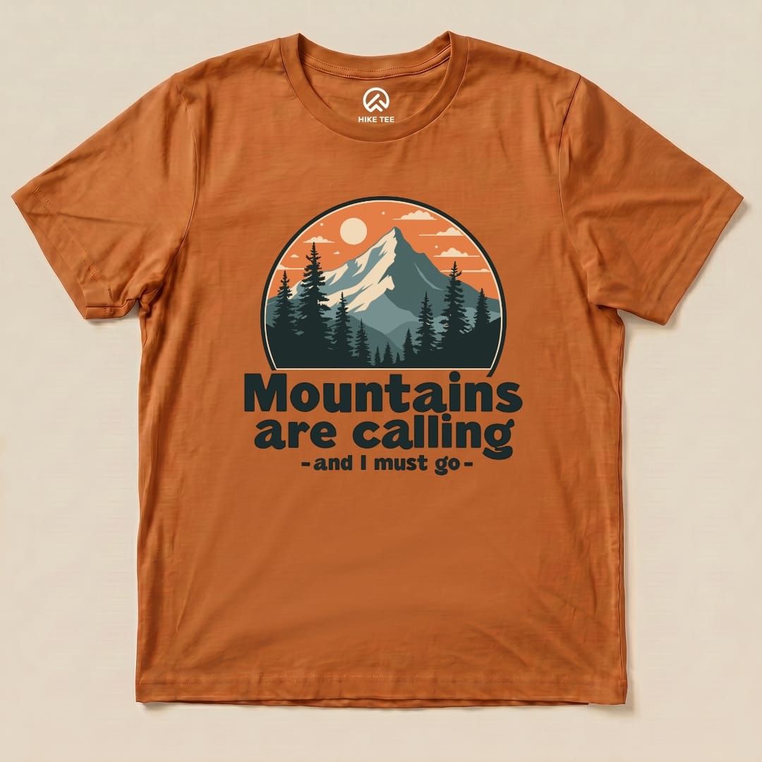 The orange graphic t-shirt features a mountain scene with the text "Mountains are calling - and I must go" prominently displayed.