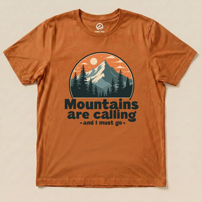 The orange graphic t-shirt features a mountain scene with the text "Mountains are calling - and I must go" prominently displayed.