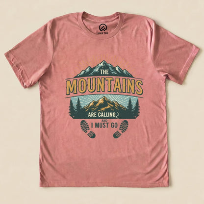 The graphic t-shirt features a design with mountains and trees, along with the text "The Mountains Are Calling and I Must Go.