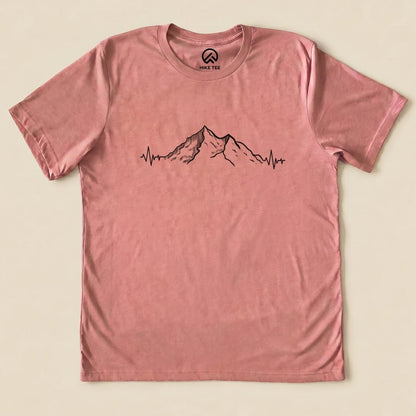 A flat graphic t-shirt in a pink hue featuring a mountain design with heart rate lines, labeled as "Mountains Heart Rate Shirt.