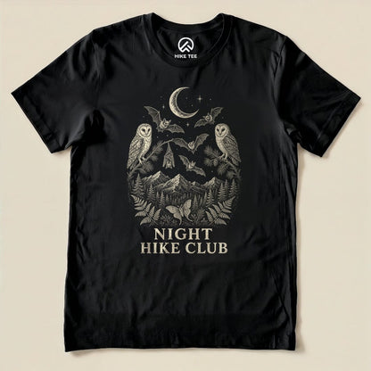A black graphic t-shirt featuring the "Night Hike Club Engraved Shirt" design with owls, bats, and mountains surrounding the text.