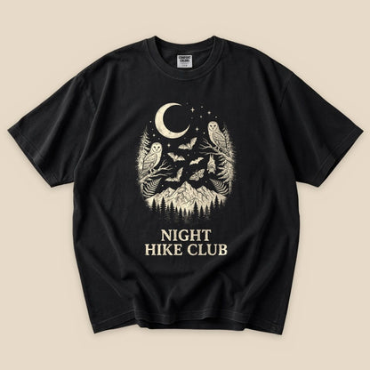 Black graphic t-shirt featuring a moonlit design with owls, bats, and mountains, labeled "Night Hike Club" at the bottom.