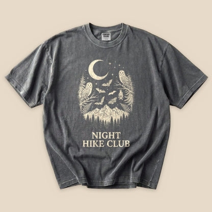 A graphic t-shirt featuring an owl and bats design with a mountain backdrop, labeled "NIGHT HIKE CLUB.