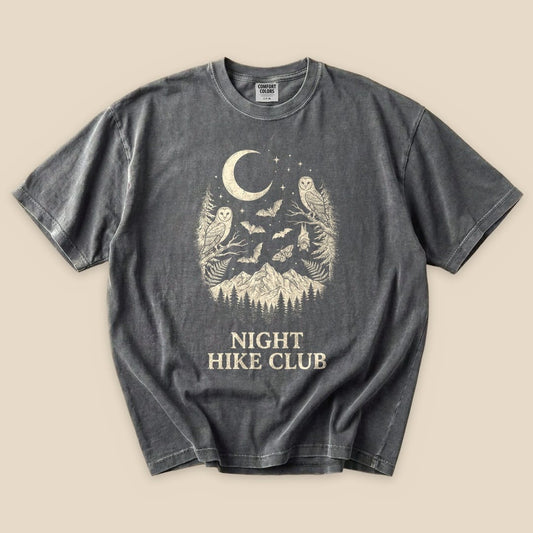 A graphic t-shirt featuring an owl and bats design with a mountain backdrop, labeled "NIGHT HIKE CLUB.