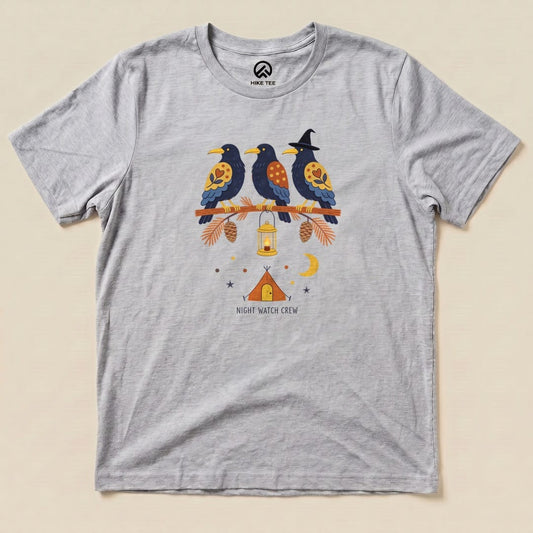 A light gray graphic t-shirt features three colorful birds perched on a branch with the text "NIGHT WATCH CREW" and camping elements.