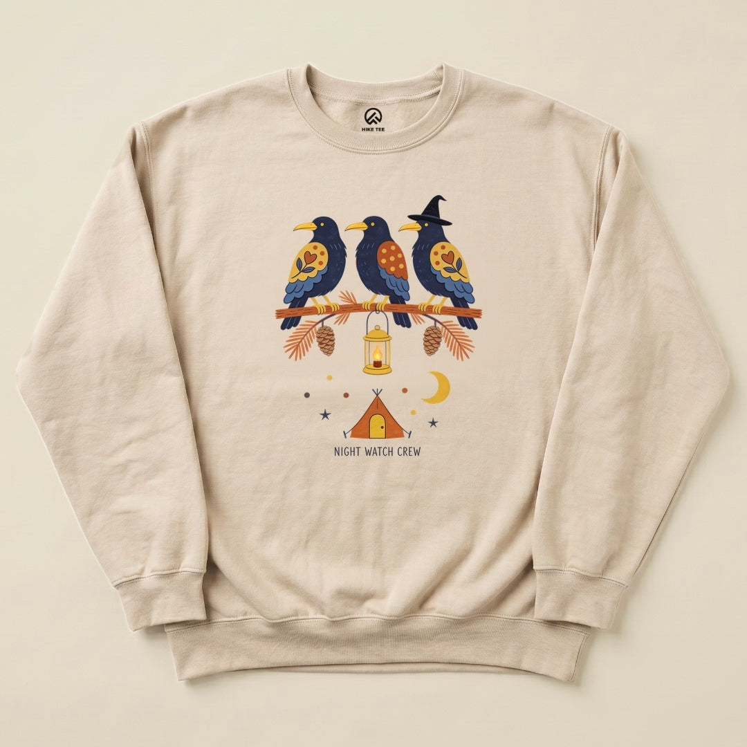 Sand Night Watch Crew Sweatshirt with a folk-art crow trio on a pine branch with a lantern above a tent graphic