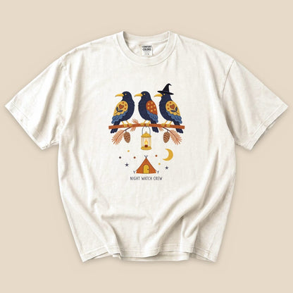 Graphic t-shirt featuring three colorful birds on a branch, a lantern, and "NIGHT WATCH CREW" printed underneath.