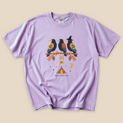 The lavender graphic t-shirt features three stylized birds perched on a branch, with a lantern and a crescent moon, labeled "NIGHT WATCH CREW.