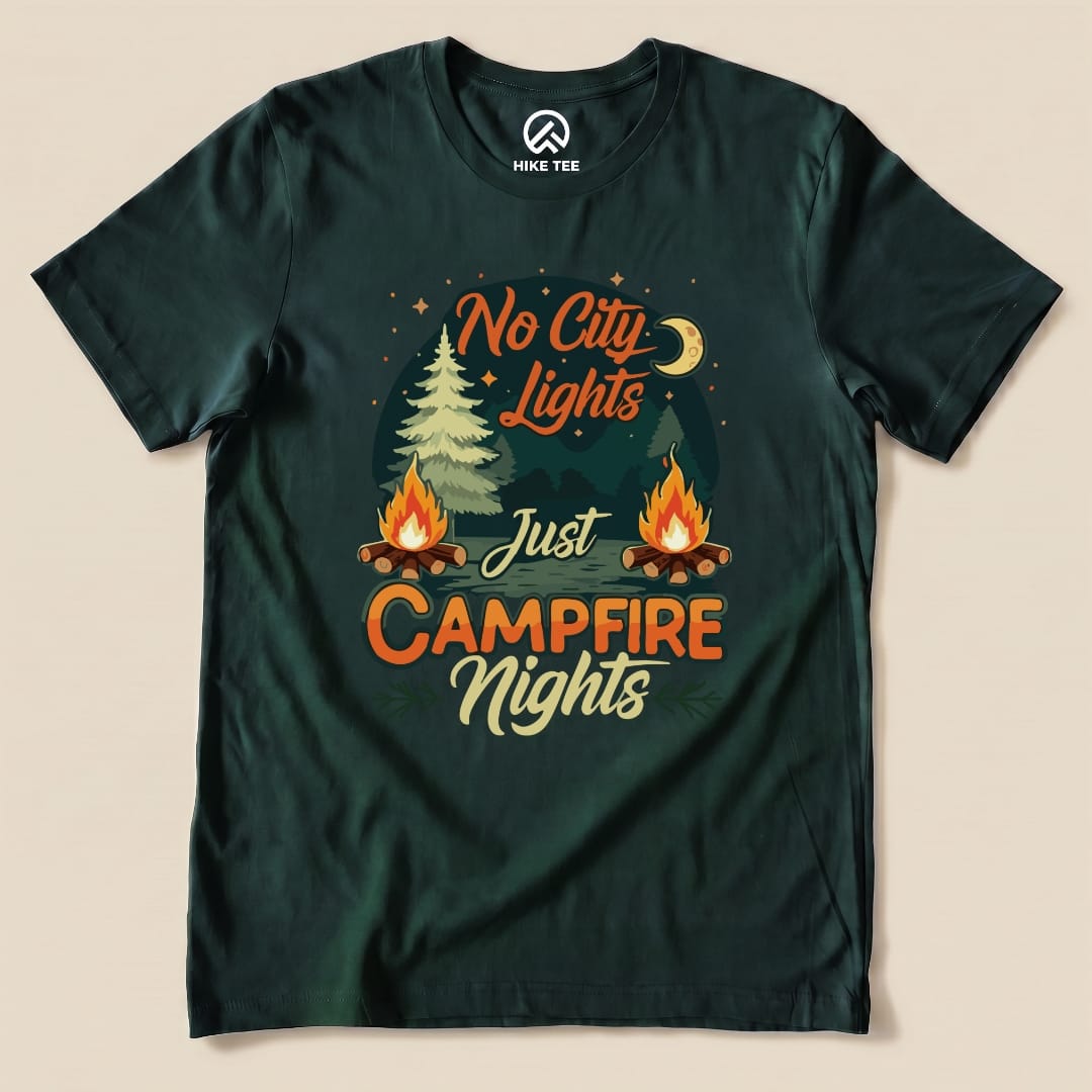 A dark green graphic t-shirt featuring the slogan "No City Lights Just Campfire Nights" with campfire and forest imagery.