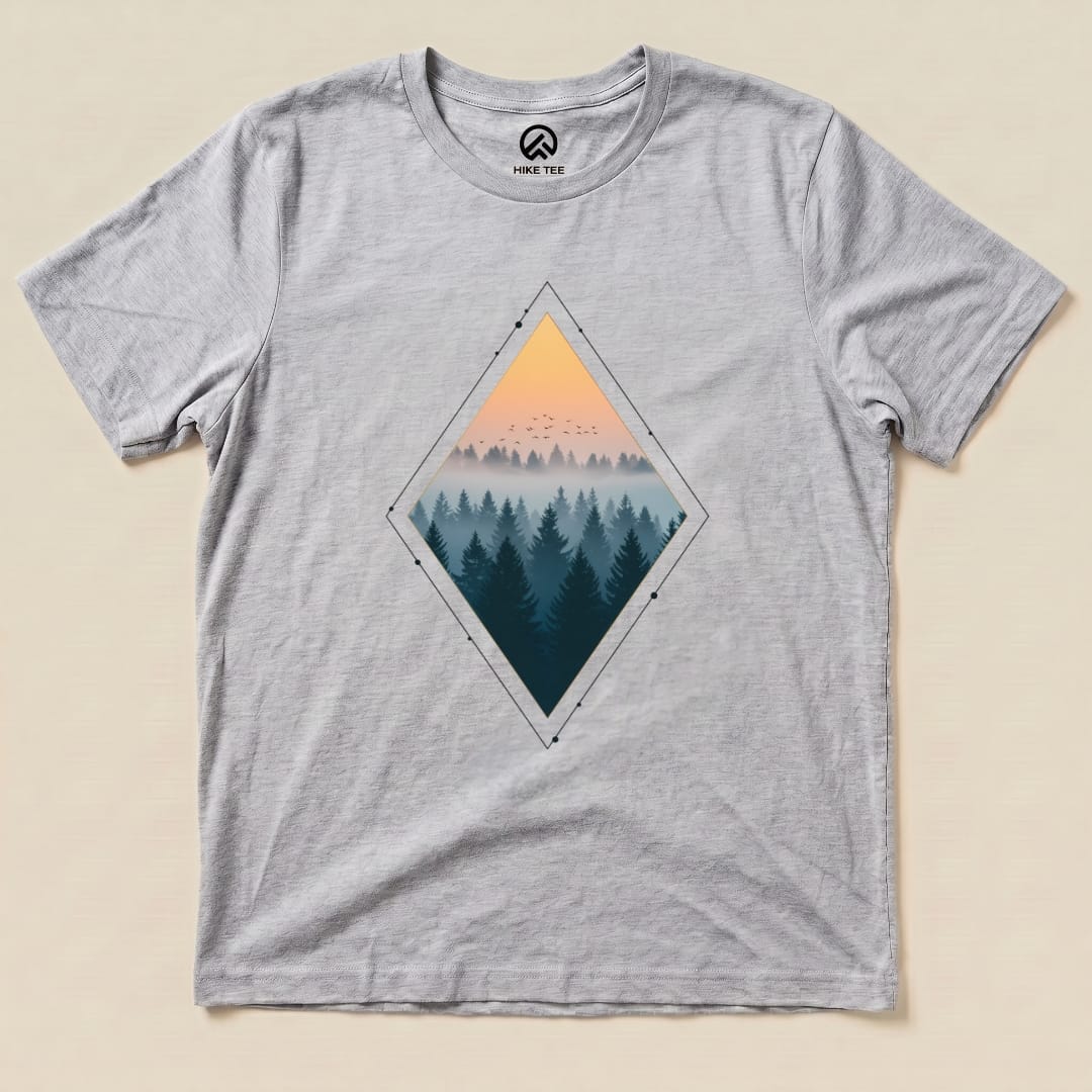 A graphic t-shirt featuring a diamond-shaped design of a misty forest at sunset, titled "Nostalgic Forest Shirt.