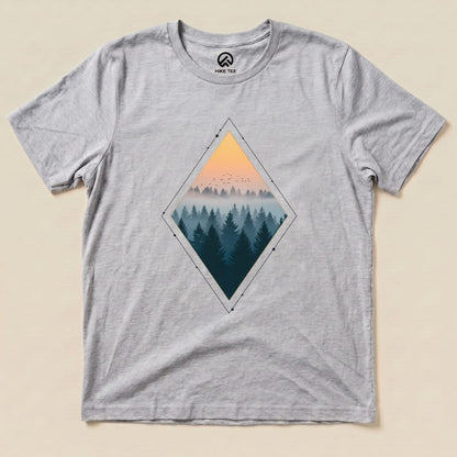 A graphic t-shirt featuring a diamond-shaped design of a misty forest at sunset, titled "Nostalgic Forest Shirt.