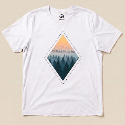 A white graphic t-shirt featuring the "Nostalgic Forest Shirt" design, showcasing a diamond-shaped print of serene forest silhouettes and a sunrise.