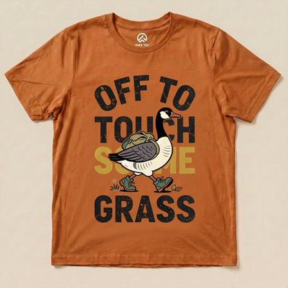The Hike Tee "Off To Touch Some Grass Shirt" features a cartoon goose walking with a backpack, surrounded by bold text.