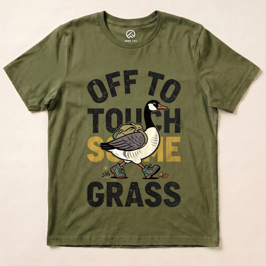 Olive green graphic t-shirt featuring a quirky goose illustration and the text "OFF TO TOUCH SOME GRASS" in bold letters.