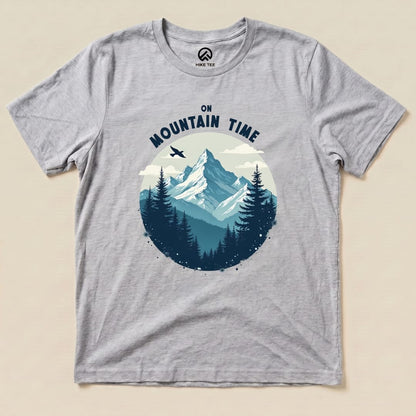 A gray graphic t-shirt featuring a mountain scene with the words "ON MOUNTAIN TIME" arching above the design.