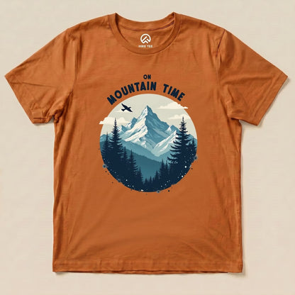 A graphic t-shirt featuring mountains, pine trees, and the text "On Mountain Time" in bold lettering on an orange background.