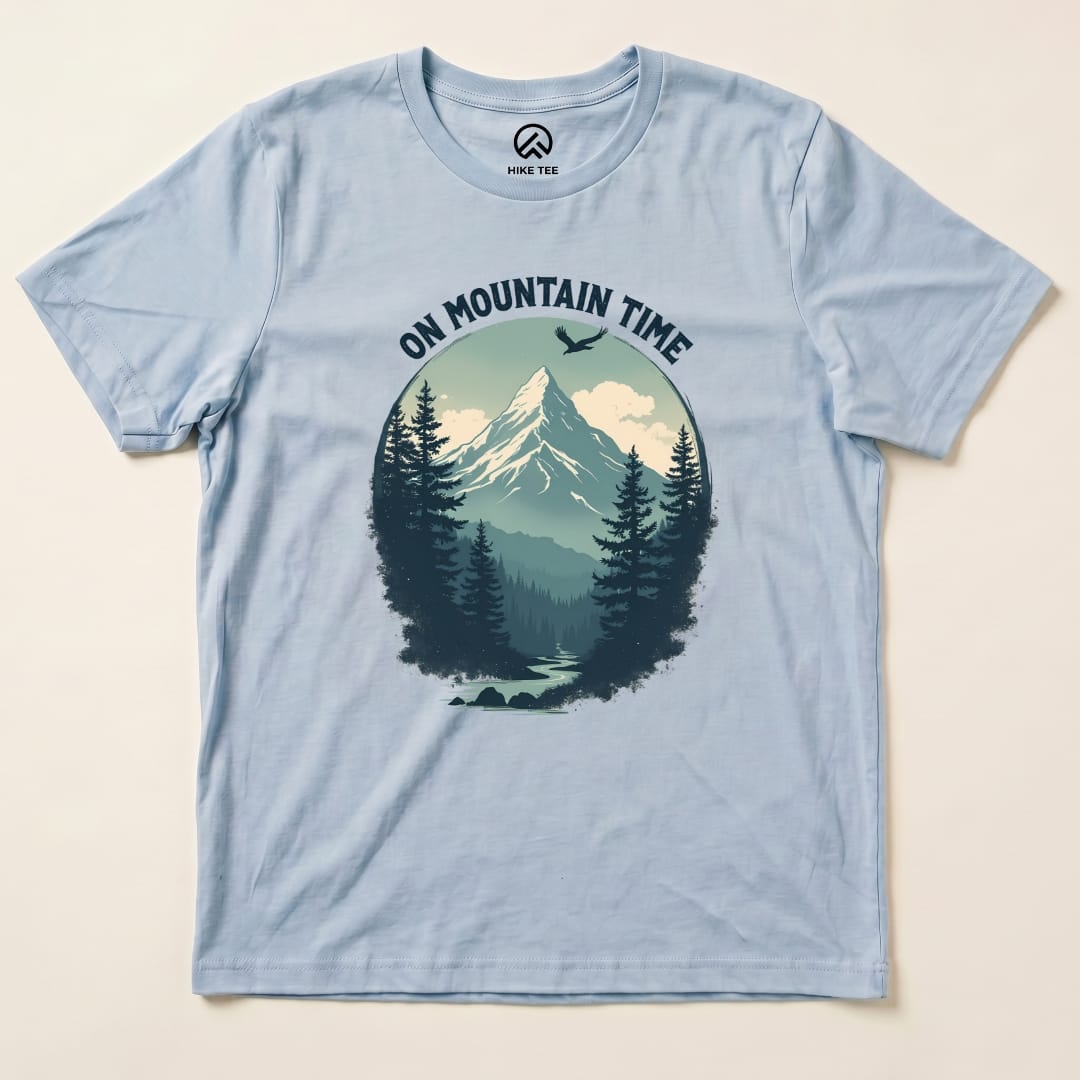 A light blue graphic t-shirt featuring the phrase "ON MOUNTAIN TIME" above a scenic design of mountains and trees.