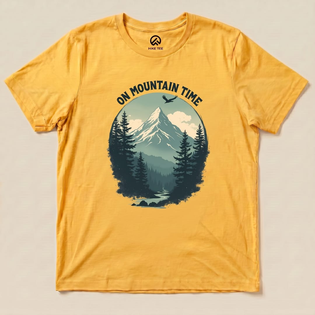 Graphic t-shirt in a vibrant yellow featuring a scenic mountain landscape and the slogan "ON MOUNTAIN TIME" printed in bold text.