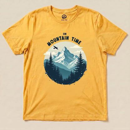 A golden yellow graphic t-shirt featuring a mountain scene with the phrase "On Mountain Time" above the design.
