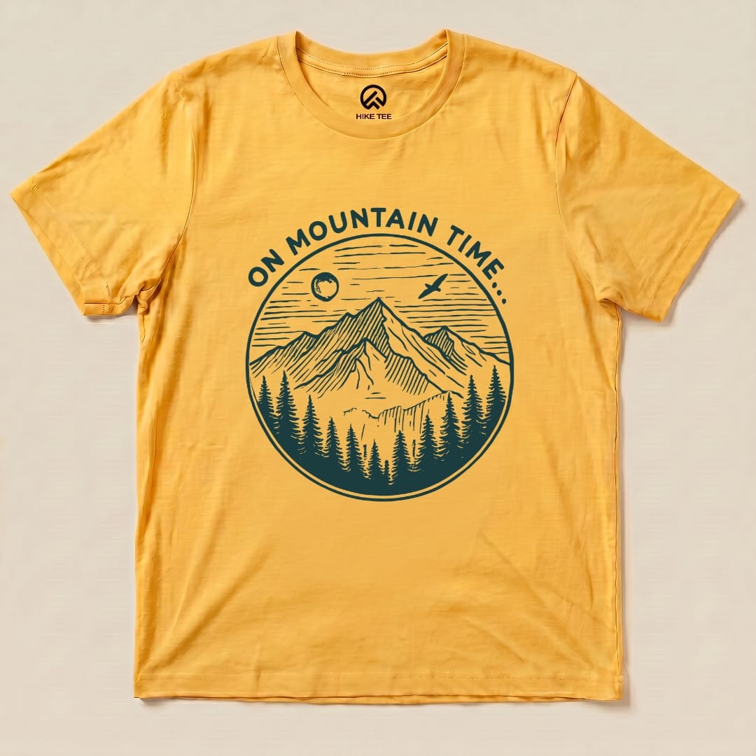 A yellow graphic t-shirt featuring the phrase "ON MOUNTAIN TIME..." alongside an illustration of mountains and trees.