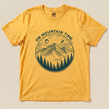 A yellow graphic t-shirt featuring the phrase "ON MOUNTAIN TIME..." alongside an illustration of mountains and trees.