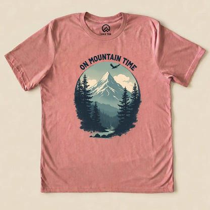 A pink graphic t-shirt features a mountain scene with pine trees and the phrase "ON MOUNTAIN TIME" arching above the design.